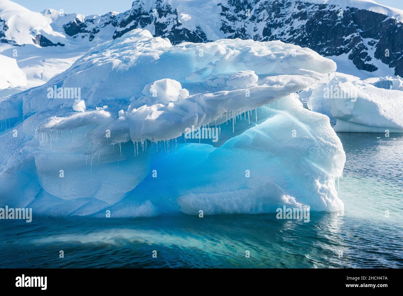 Una fotografia di paesaggio di un iceberg, ghiacci e ghiaccio blu e uno sfondo di montagne innevate a Danco Island, Antartide Foto Stock