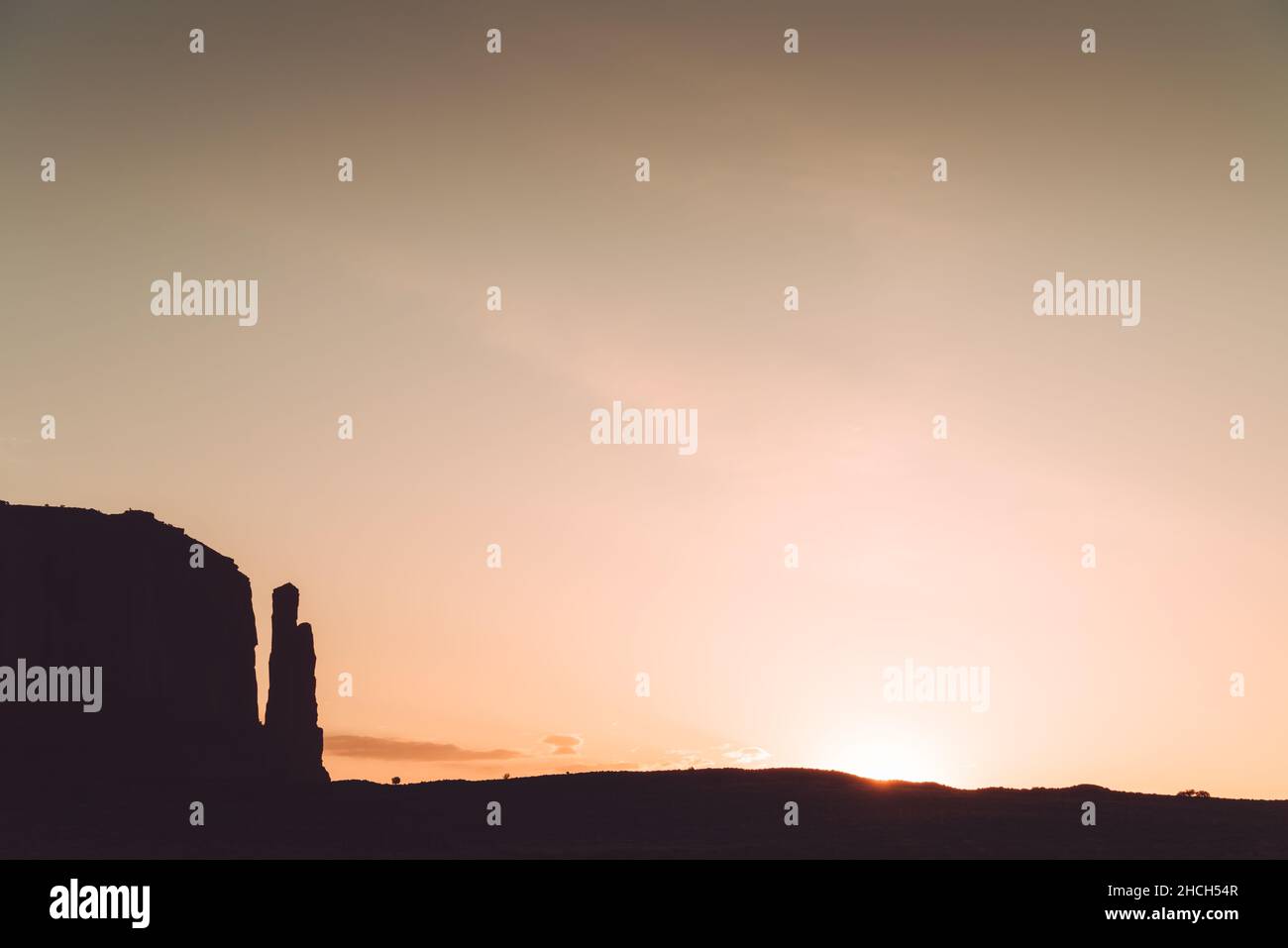 Silhouette di formazioni rocciose nella Monument Valley con il sole che appare Foto Stock