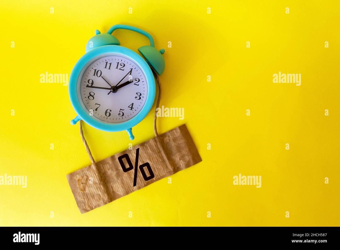 Icona percentuale tasso di interesse su sfondo giallo con un orologio. Concetto di tassi di interesse finanziari e ipotecari. Foto Stock
