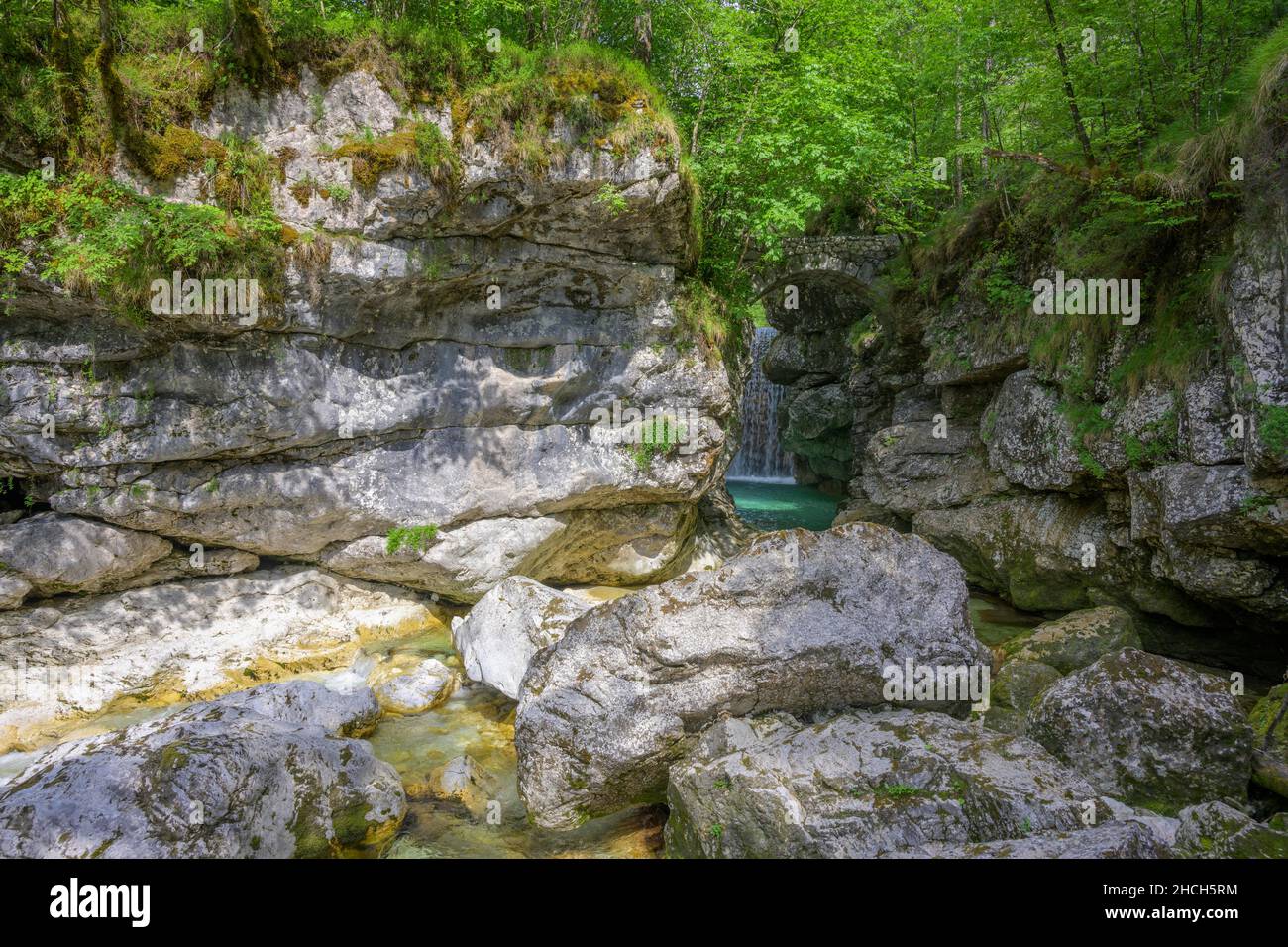 Cascata Rio Repepeit una piccola cascata artificiale con ponte di pietra, CHIUSAFORTE, provincia di Udine, Italia Foto Stock