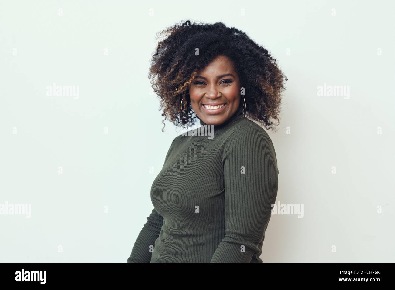 Donna allegra con capelli crespi su sfondo bianco. Sorridente Foto Stock