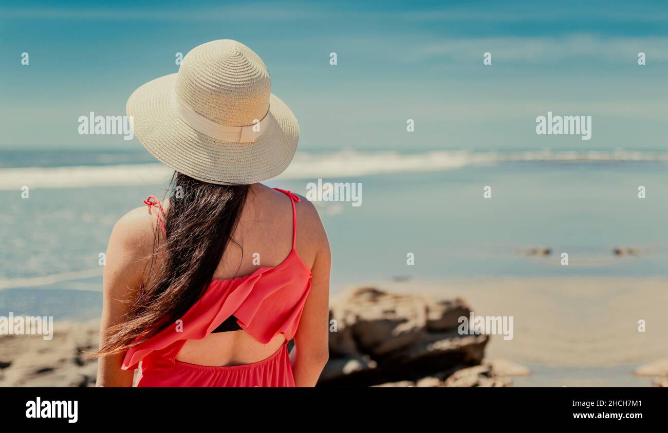 Donna in cappello dal ritorno al mare, ragazza in cappello guardando al mare, concetto di vacanza, vista posteriore di una ragazza che guarda il mare Foto Stock