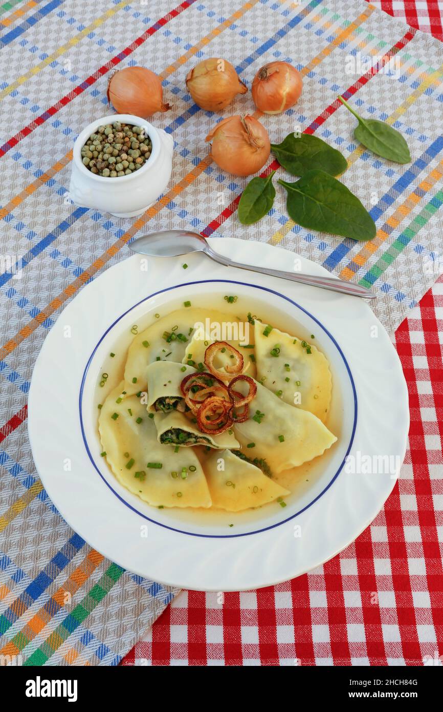 Cucina sveva, Maultaschen in brodo con anelli di cipolla stufati e erba cipollina, piatto per zuppa, cucchiaio, pepe verde, Germania Foto Stock