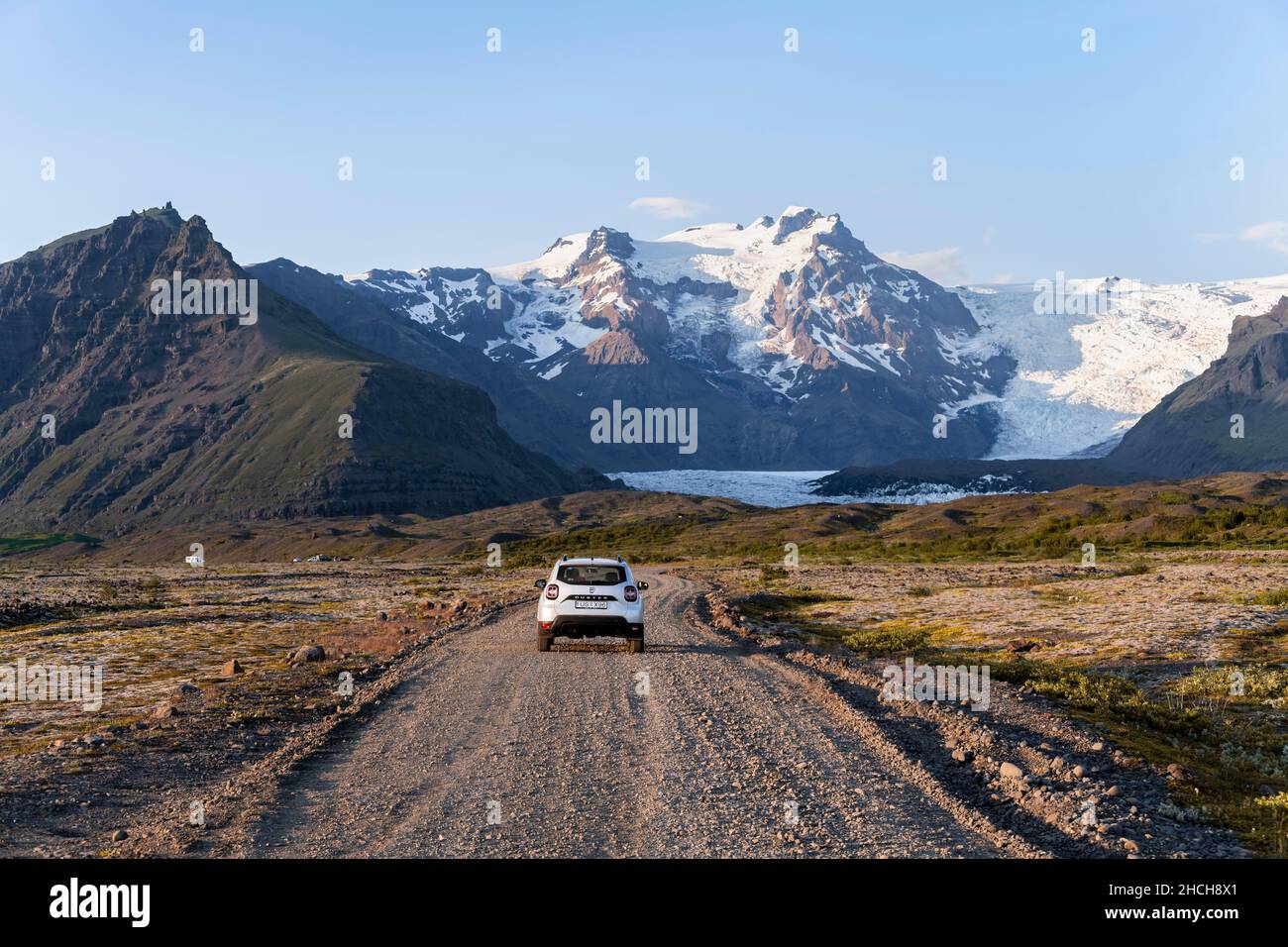 Auto su strada di ghiaia, ghiacciaio Vatnajoekull, montagne e ampio paesaggio dietro, Ring Road, Islanda Foto Stock