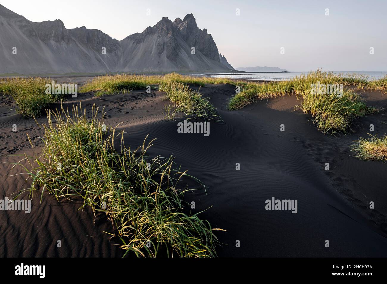 Spiaggia di lava nera, spiaggia sabbiosa, dune con erba secca, promontorio di Stokksnes, catena montuosa di Klifatindur, Austurland, Islanda orientale, Islanda Foto Stock