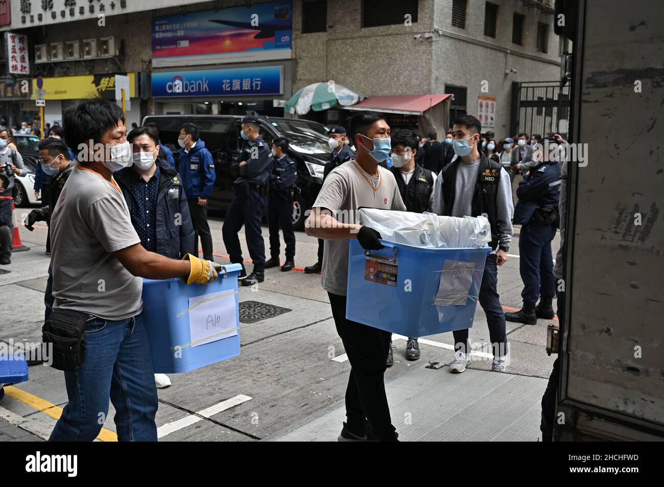 Lam Tin, Cina. 29th Dic 2021. Gli agenti di polizia trasportano i materiali di notizie in scatole di plastica blu dopo la ricerca dell'ufficio di Stand News.Aid la soppressione politica, il servizio indipendente di notizie di Hong Kong è stato razziato e cercato da 200 agenti di polizia. Notizie stand i membri del consiglio editoriale, i redattori e il membro del consiglio di amministrazione, il cantante pop Denis ho, sono stati arrestati. Credit: SOPA Images Limited/Alamy Live News Foto Stock