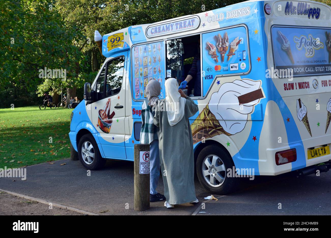 Il signor Whippy gelato furgone al parco con due donne che ricevono gelati Foto Stock