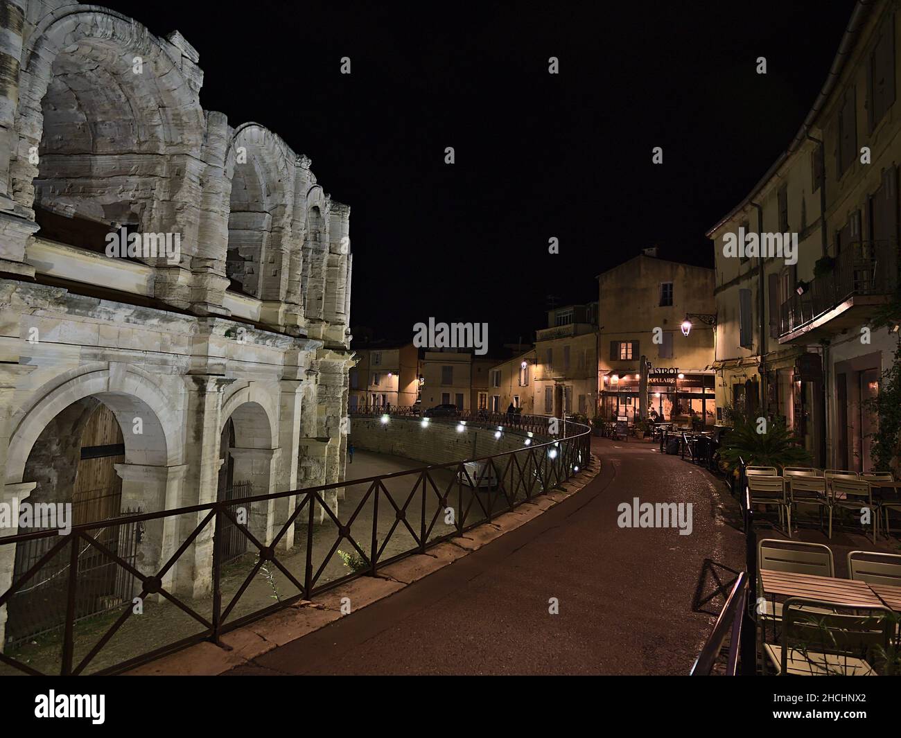 Bella vista notturna del centro storico di Arles, Provenza, Francia in serata con anfiteatro romano illuminato e ristoranti. Foto Stock