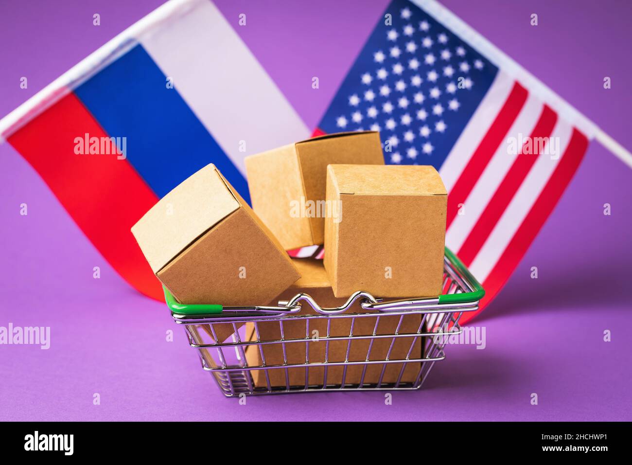 Varie scatole in un cestino di cibo e bandiere di Russia e America su uno sfondo colorato, il concetto di commercio tra i paesi dell'America e Russ Foto Stock