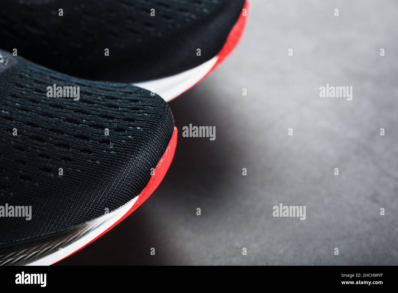 Scarpe da running nere con rete e lacci neri da vicino su sfondo scuro. Vista dall'alto delle sneaker sportive. Foto Stock