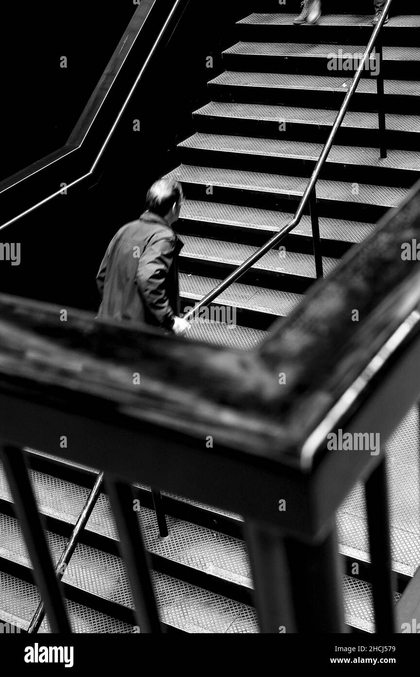 Scatto ad angolo alto di un uomo che salirà le scale in bianco e nero Foto Stock