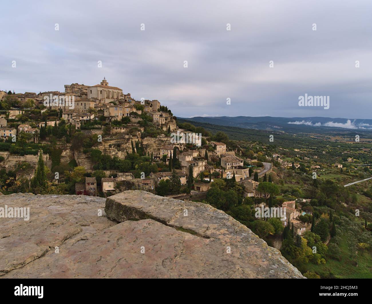 Bella vista del villaggio storico Gordes con vecchi edifici situati su una collina rocciosa sopra la valle del Luberon nella regione della Provenza, Francia in giornata nuvolosa. Foto Stock