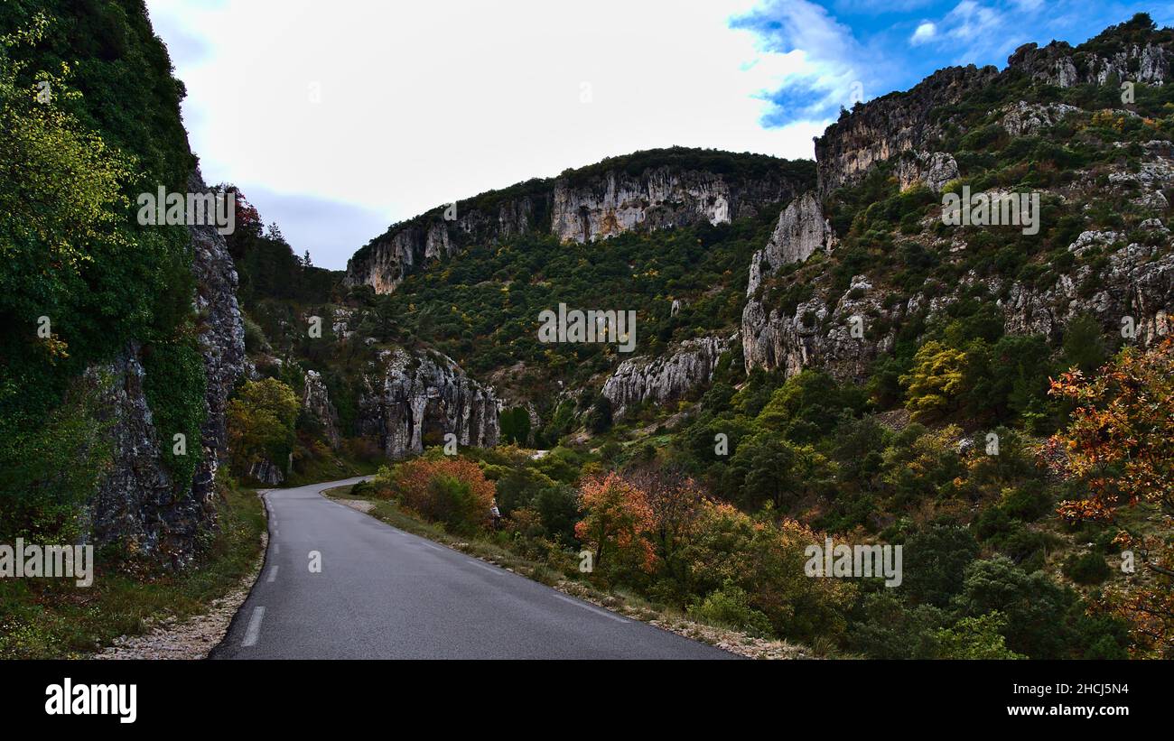 Vista della strada asfaltata di campagna D177 che attraversa un canyon roccioso nelle montagne rurali Vaucluse vicino Gordes, Francia nella regione della Provenza in giornata nuvolosa. Foto Stock