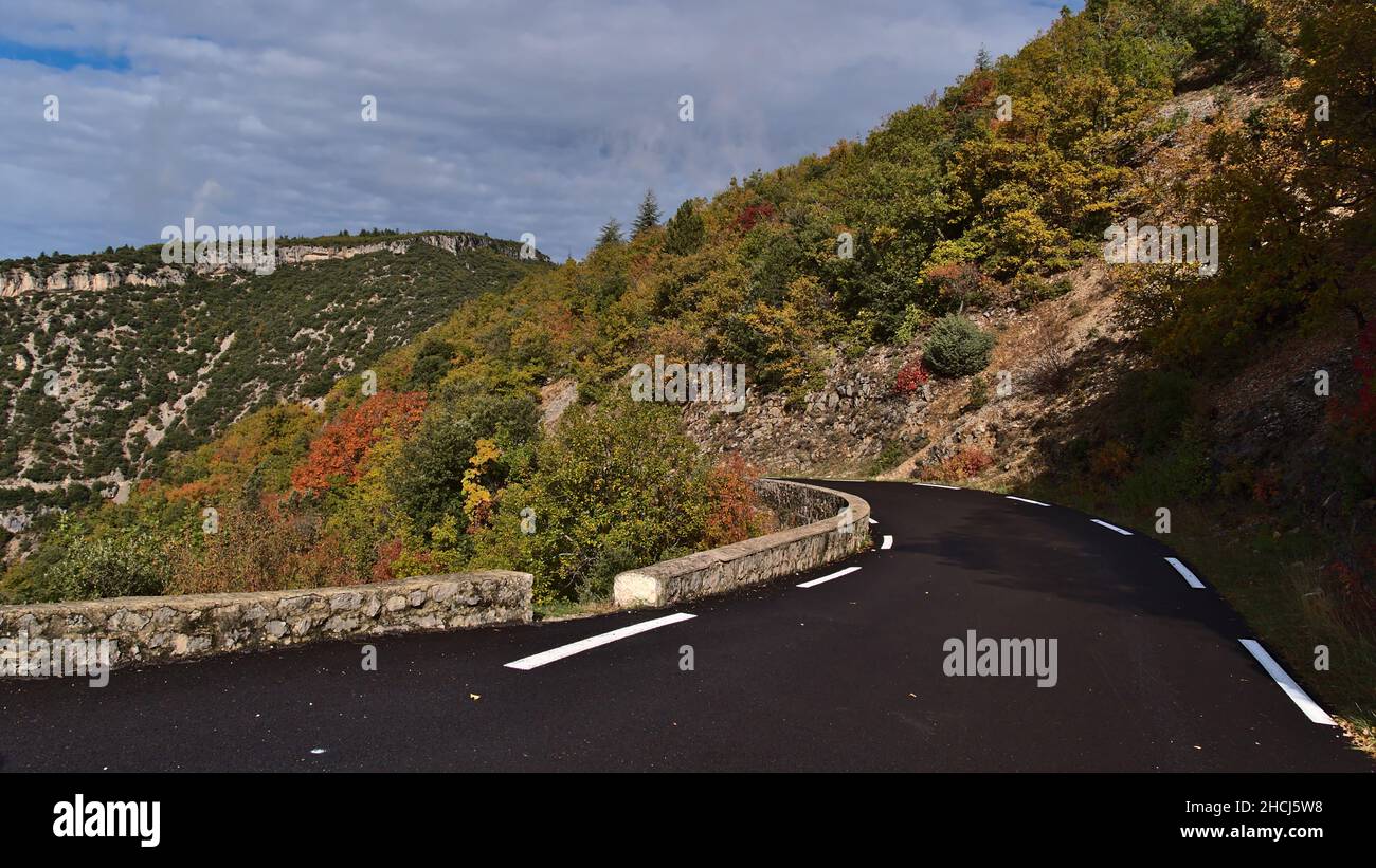 Vista della strada di campagna curvilinea D942 con asfalto nero e marcature bianche sopra le gole del canyon de la Nesque nei Monti Vaucluse in Provenza, Francia. Foto Stock