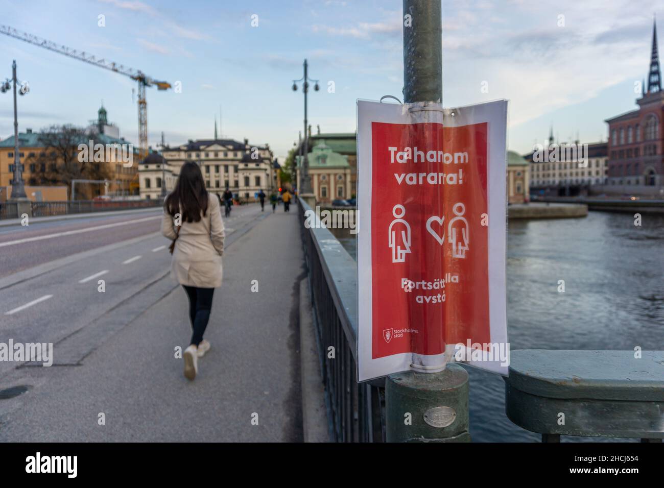 Stoccolma, Svezia - 10 maggio 2021:un cartello laminato sul lampione vicino al parlamento con il testo che dice prendersi cura l'un l'altro! Mantenere la distanza Foto Stock