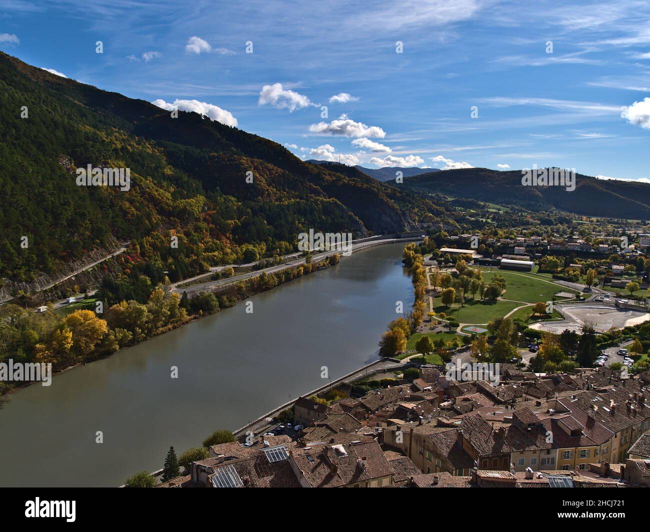 Bella vista sul fiume Durance con alberi colorati in autunno e gli edifici storici della città di Sisteron in Provenza regione, Francia. Foto Stock