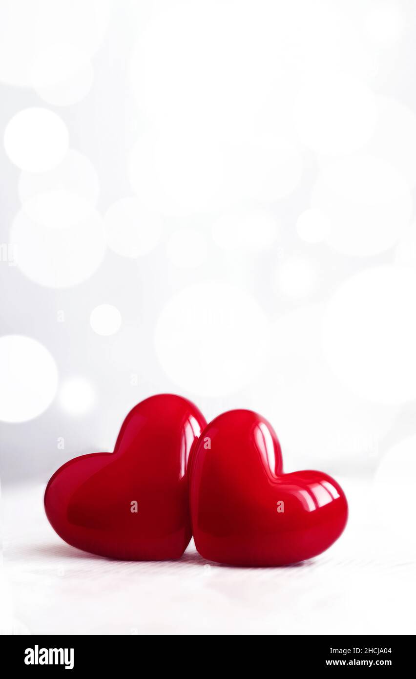Sfondo del giorno di San Valentino con cuori in plastica lucido su grigio. Biglietto giornaliero per gli amanti felici, spazio copia. Foto Stock