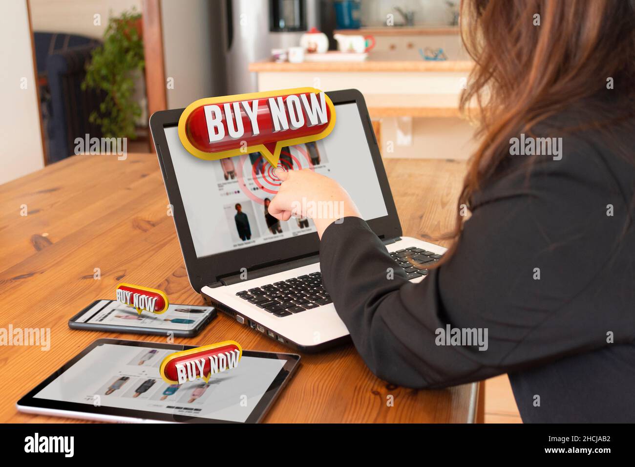 Bella donna ispanica seduta nella sua sala da pranzo facendo clic sul pulsante ACQUISTA ORA in 3 dimensioni che si apre dal suo schermo laptop Foto Stock