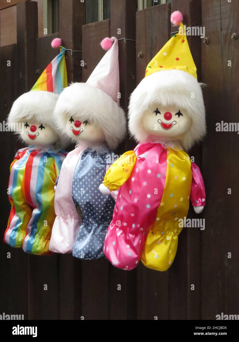 Colpo verticale di tre bambole vintage clown appese su una recinzione di legno Foto Stock