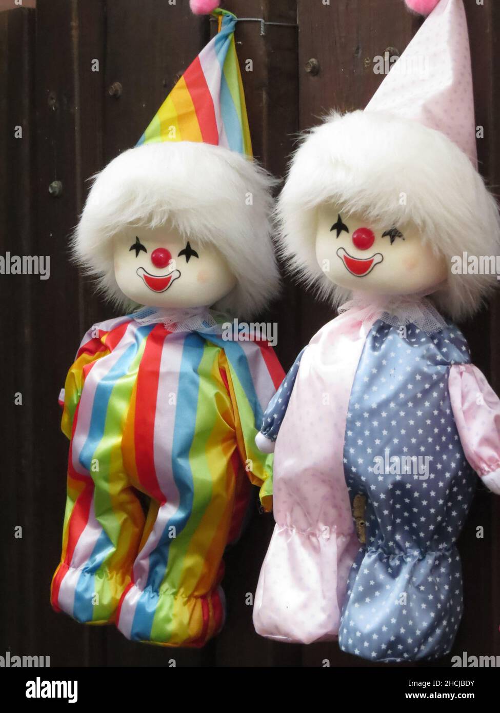 Colpo verticale di due bambole vintage clown appese su una recinzione di legno Foto Stock