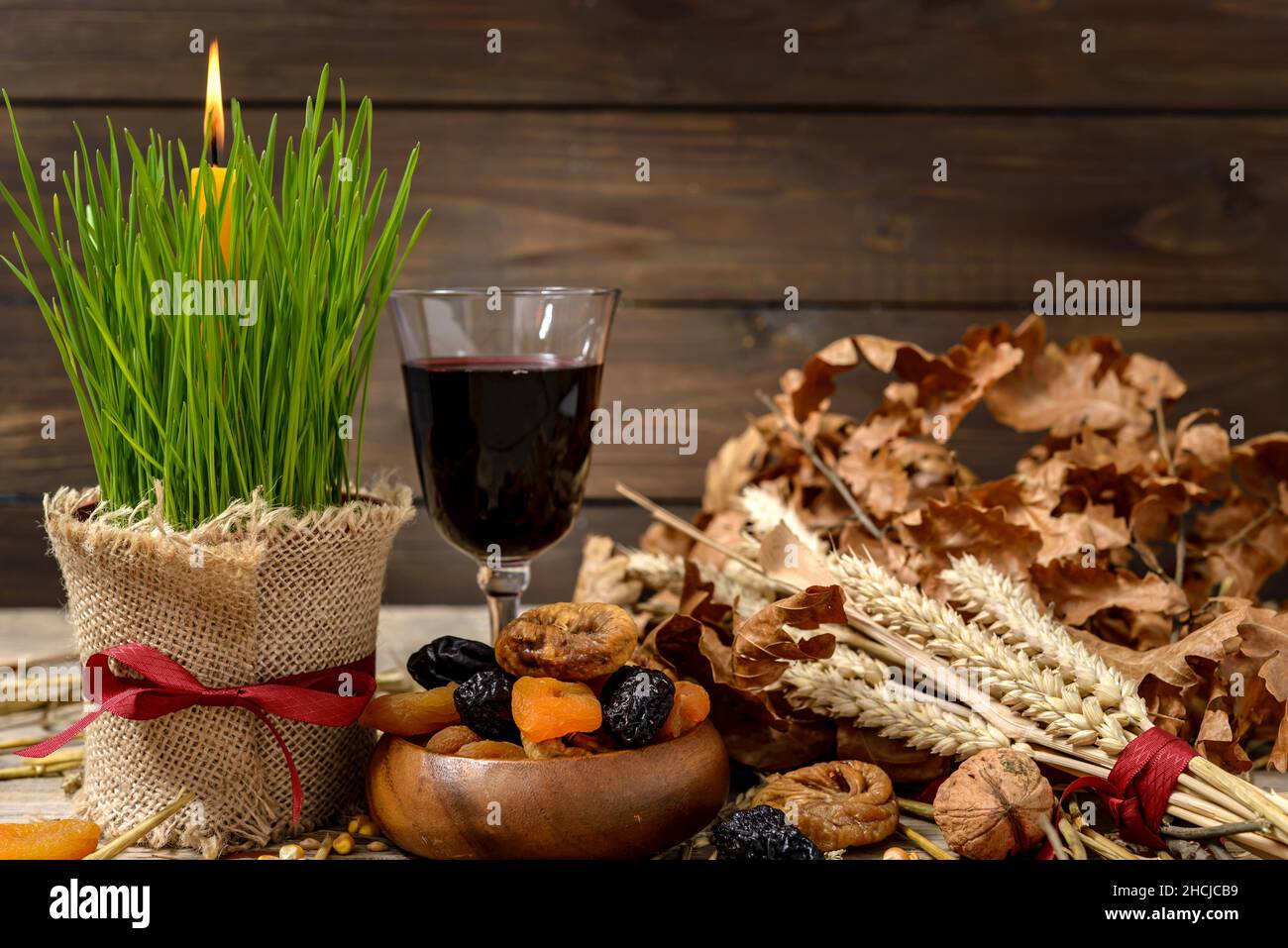 Cibo tradizionale per la vigilia di Natale ortodossa. Tronchi di Yule o badnjak, vino, mele, cereali, frutta secca e candela bruciante su tavola di legno. Concept cele Foto Stock