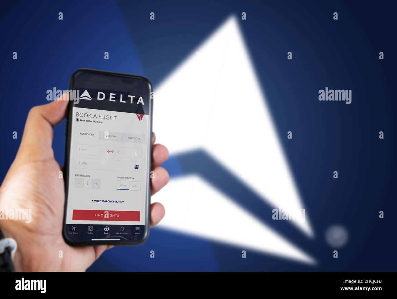 Atlanta, USA, ottobre 2021: Tenere a mano un telefono con la richiesta di prenotazione dei voli Delta Airlines. Logo Delta sfocato su sfondo blu. Delta Airlin Foto Stock