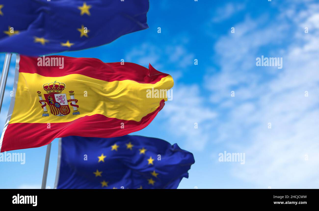 La bandiera nazionale della Spagna sventola tra due bandiere dell'Unione europea con il cielo blu sullo sfondo. Relazioni internazionali e diplomazia europea. Foto Stock