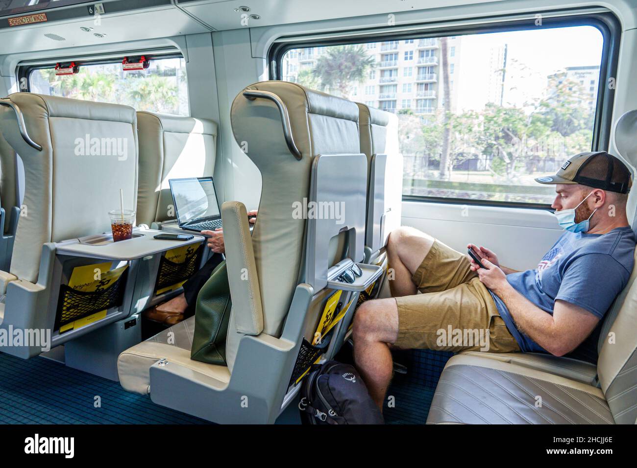 Fort ft. Lauderdale Florida Brightline passeggero treno trasporto ferroviario servizio di trasporto di massa cabina di transito interno sedili uomo maschio lettura smartphon Foto Stock