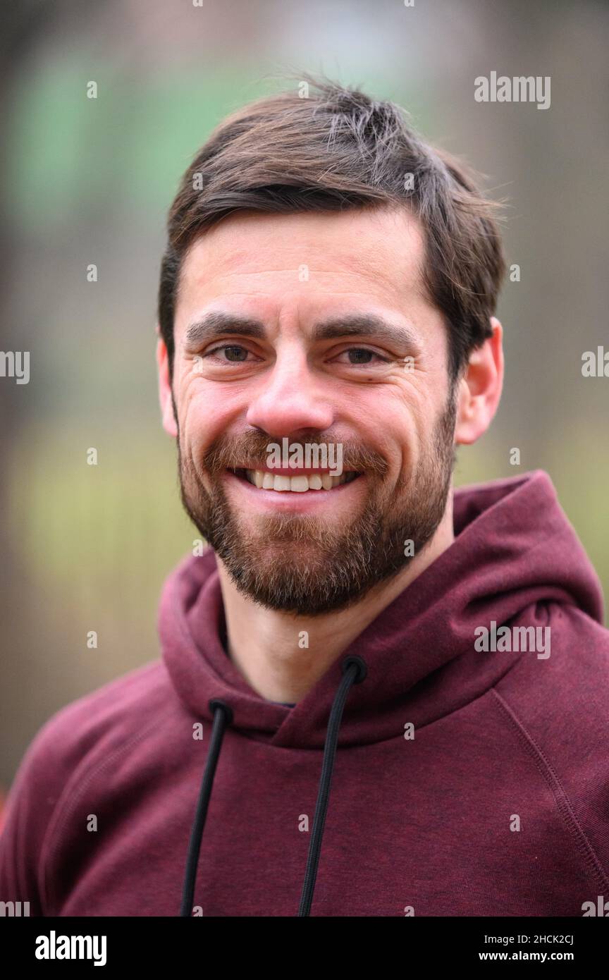 Asendorf, Germania. 29th Dic 2021. L'atleta Lars Wichert sta sorridendo nel suo giardino. Venne, vide e vinse: Lars Wichert è abituato a grandi successi. Ma il fatto che l'ex campione del mondo di canottaggio vinse ad Amburgo alla sua prima Ironman sorprende non solo lui. Si è qualificato per i campionati del mondo in Hawaii. Ora ha i suoi occhi impostato su una carriera professionale. Credit: Jonas Walzberg/dpa/Alamy Live News Foto Stock