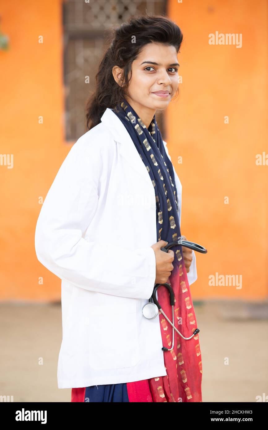 Ritratto di giovane sorridente indiano femmina Dottore tenuta stetoscopio Classifiche guardando la macchina fotografica con emozioni positive su sfondo arancione. Healt Foto Stock