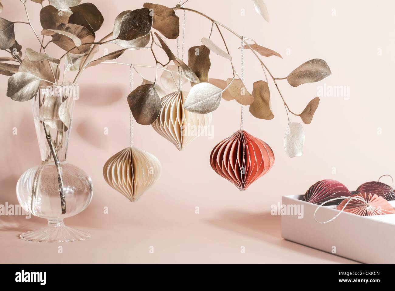 Decorazioni natalizie in carta a nido d'ape su ramo dorato su sfondo beige. Vacanze stagionali, interni, vacanze ecologiche. Foto Stock