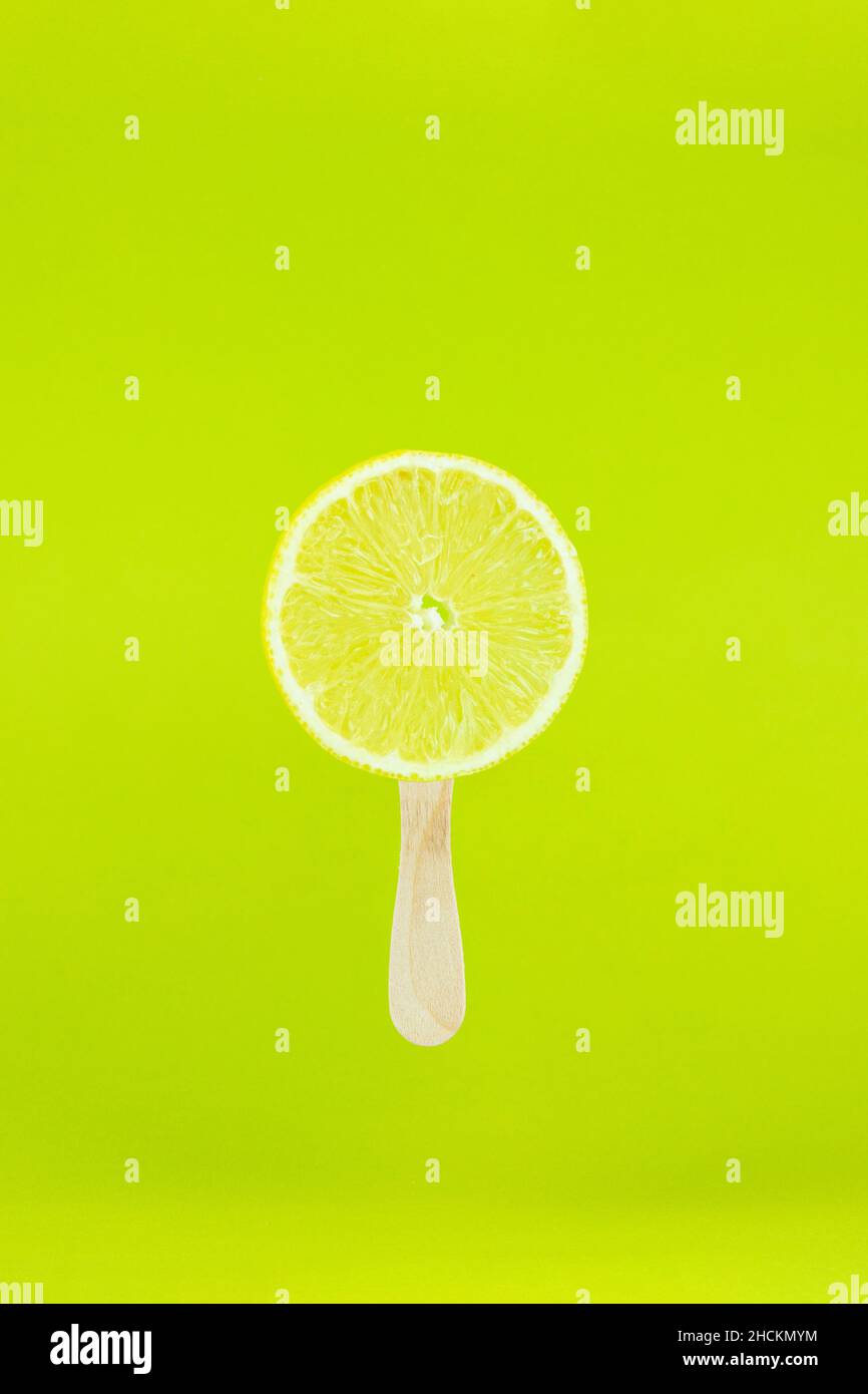 Secream al limone con bastone di legno su sfondo verde chiaro. Bastoni di papsicle dal tocco creativo e fruttato Foto Stock
