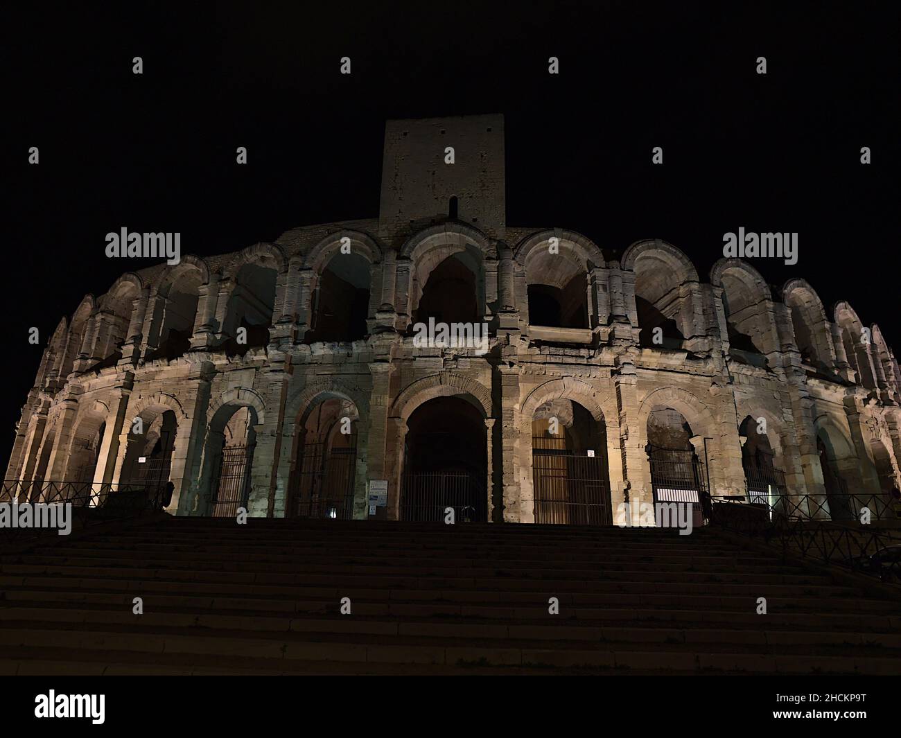 Vista dell'antico anfiteatro romano, patrimonio dell'umanità dell'UNESCO, nel centro storico di Arles, Provenza, Francia di notte con facciata illuminata. Foto Stock