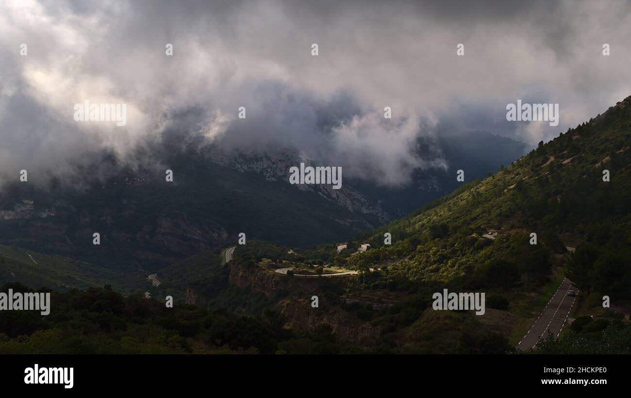 Vista mozzafiato della catena montuosa Massif de la Sainte-Baume nella regione della Provenza, Francia in giornata nuvolosa nella stagione autunnale con tortuosa strada di campagna D2. Foto Stock