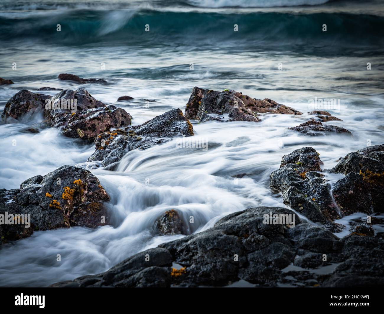 Vista mozzafiato dell'acqua schiumosa che scorre su una spiaggia rocciosa Foto Stock