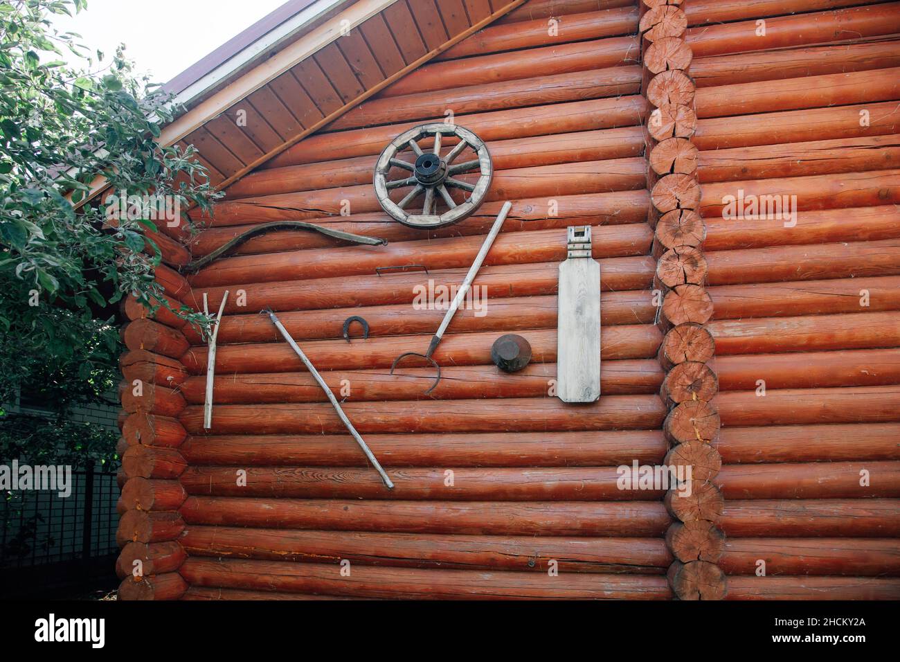 Casetta in legno di blocco di campagna con agricoltura agricoltura giardino attrezzature antiche attrezzi collegati alla facciata della casa in giorno in estate. La vita dentro Foto Stock