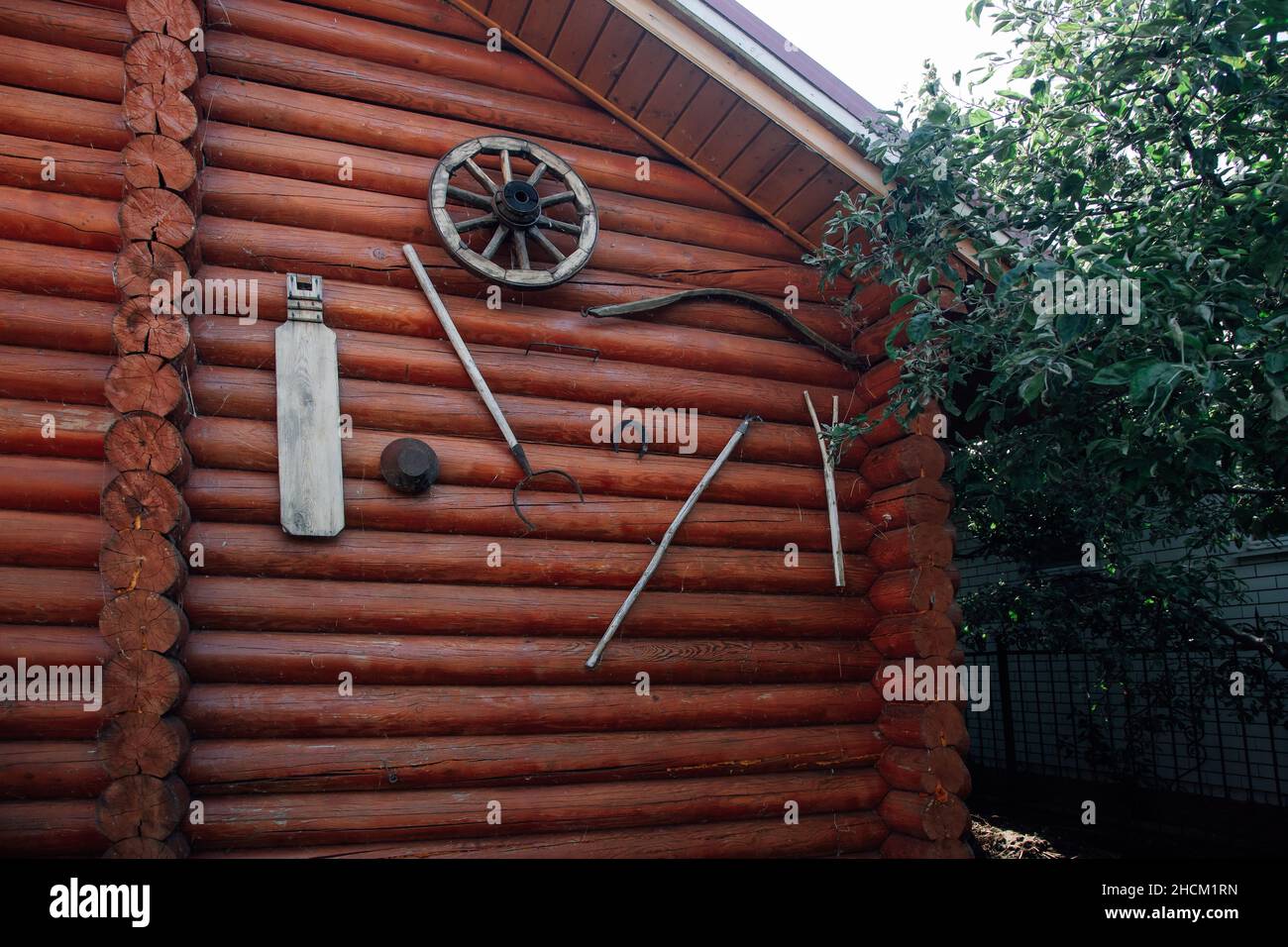 Blocco di legno di campagna edificio con antica agricoltura attrezzature agricole attrezzi da giardino attaccato alla facciata della casa in estate di giorno. Vita di villaggio Foto Stock