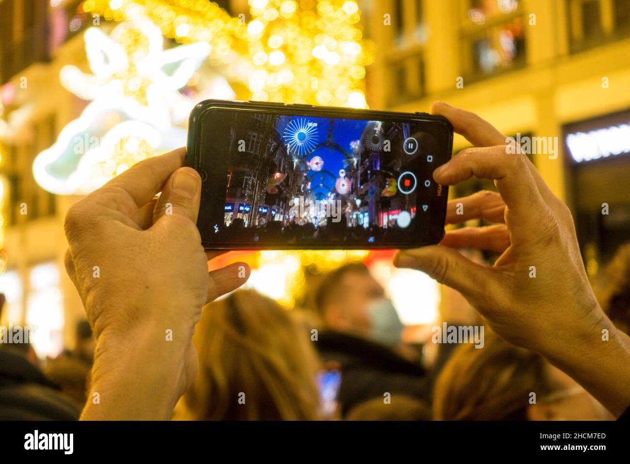 Donna, tenendo cellulare per registrare le luci di Natale, Malaga, Spagna. Foto Stock