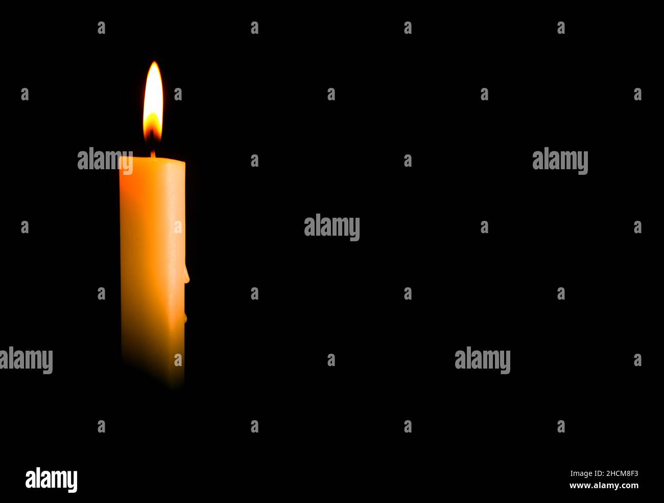 La luce della candela brucia luminosamente nello sfondo nero, lo sfondo bianco e largo per lo spazio di copia. Foto Stock
