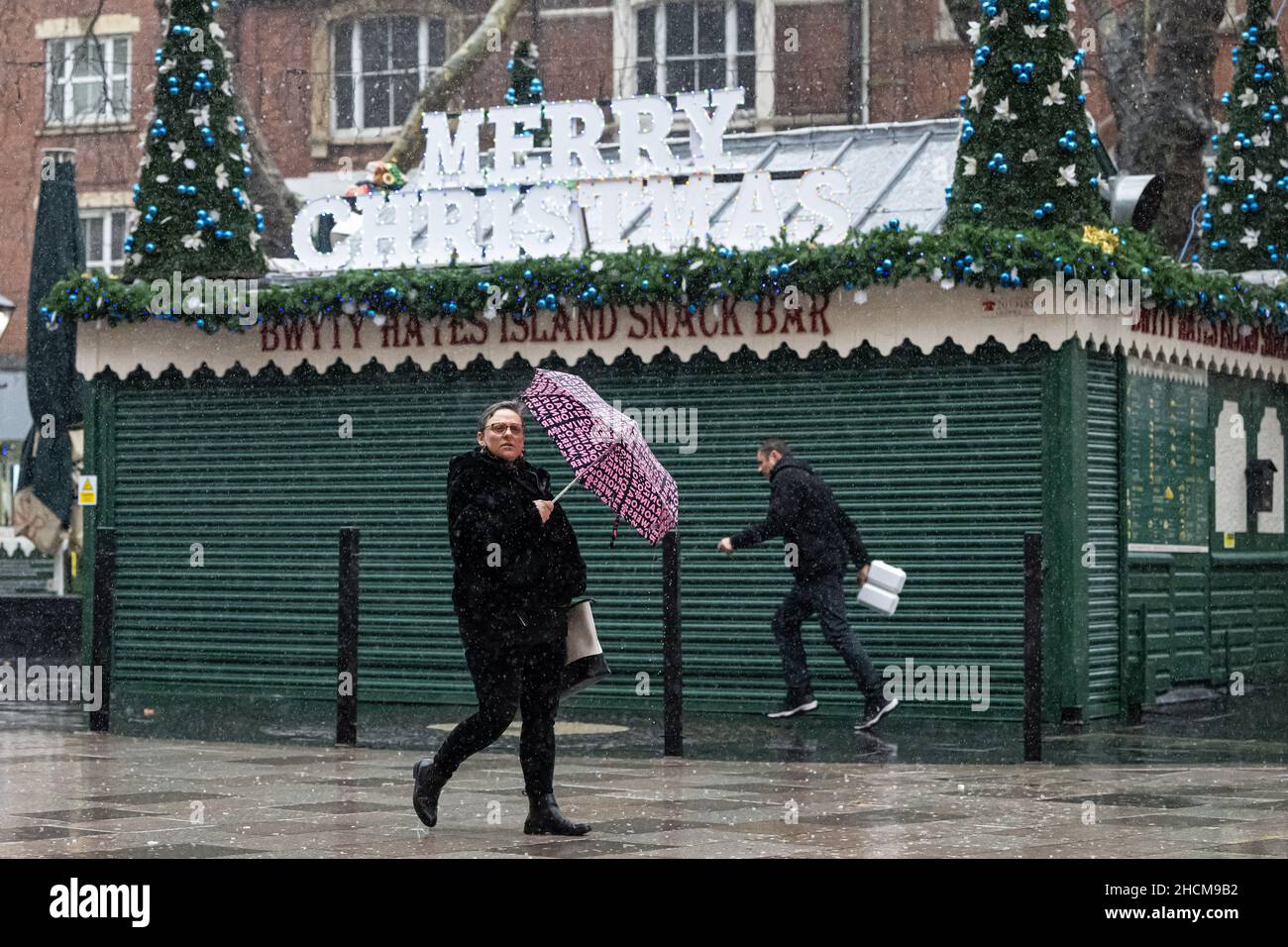 CARDIFF, GALLES - 24 DICEMBRE: Gli acquirenti di Hayes sotto la pioggia il 24 dicembre 2021 a Cardiff, Galles. Foto Stock