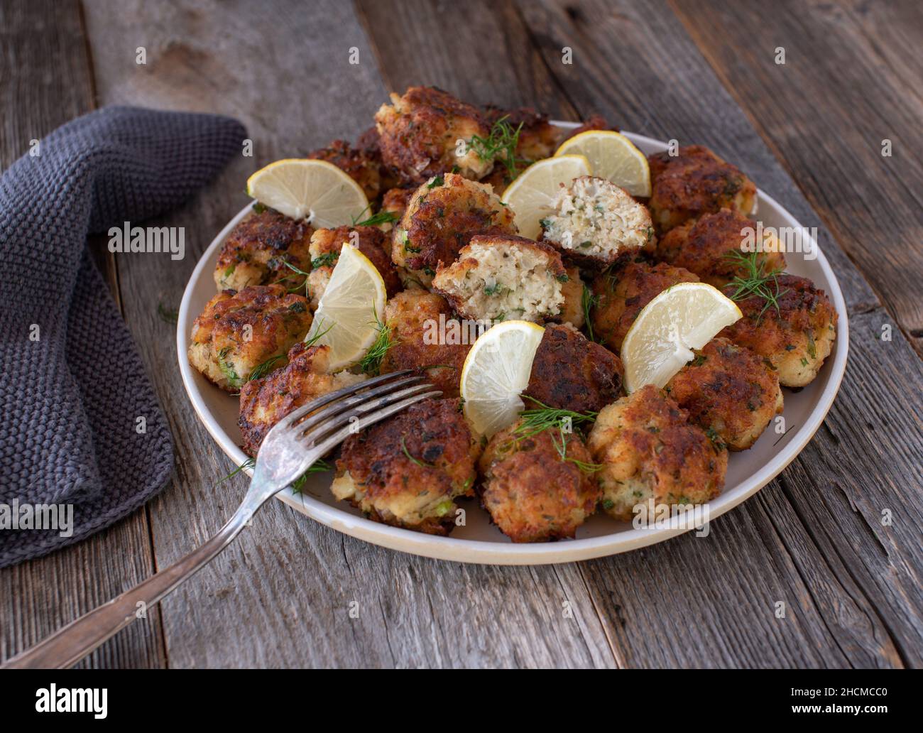Palle di pesce fritte in padella fresche fatte in casa. Servito su un piatto isolato su sfondo tavolo di legno. Foto Stock