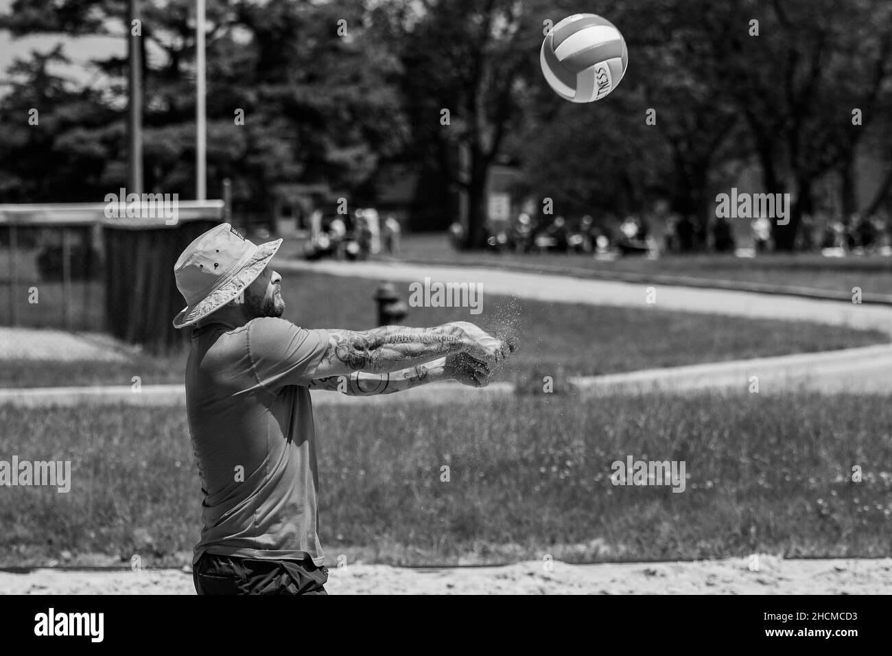 Primo piano girato in B&W di un uomo tatuato facendo un passo in azione di Beach volley Foto Stock