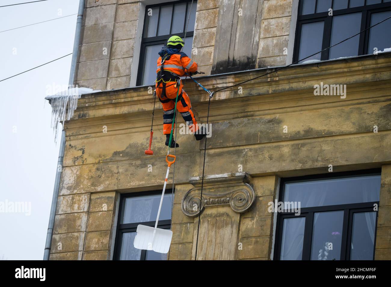 RIGA, LETTONIA. 30th dicembre 2021. Gli scalatori puliscono il ghiaccio e la neve dal tetto. Foto Stock