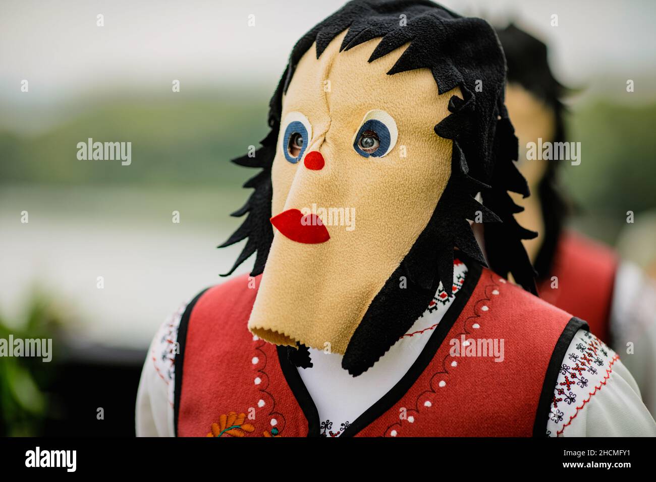 Braila, Romania - 26 agosto 2021: Donna vestita con costumi tradizionali rumeni e con maschera rituale doppia faccia esegue una danza tradizionale. Foto Stock