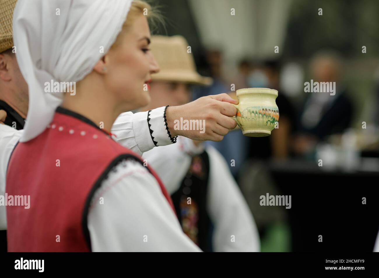 Braila, Romania - 26 agosto 2021: Uomini e donne vestiti con costumi tradizionali rumeni eseguono una danza tradizionale e bere tuica o palinca, un Ro Foto Stock
