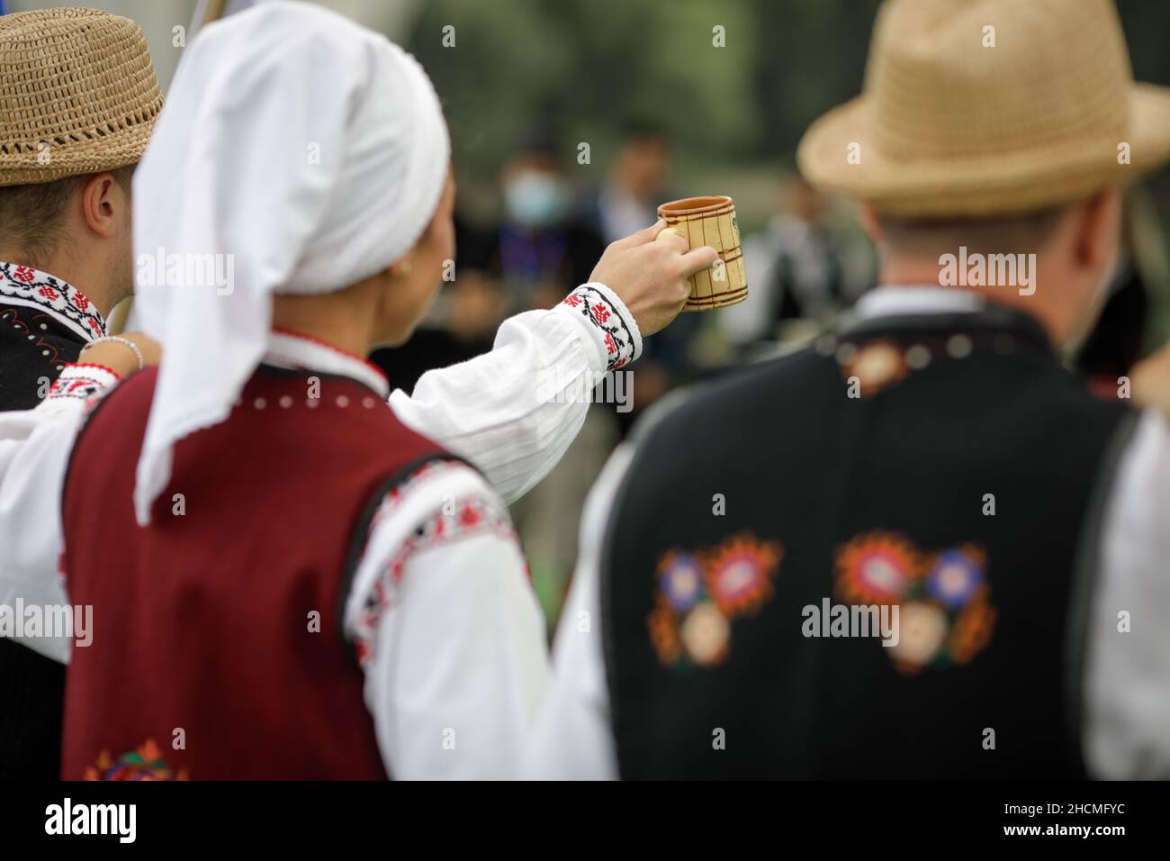 Braila, Romania - 26 agosto 2021: Uomini e donne vestiti con costumi tradizionali rumeni eseguono una danza tradizionale e bere tuica o palinca, un Ro Foto Stock