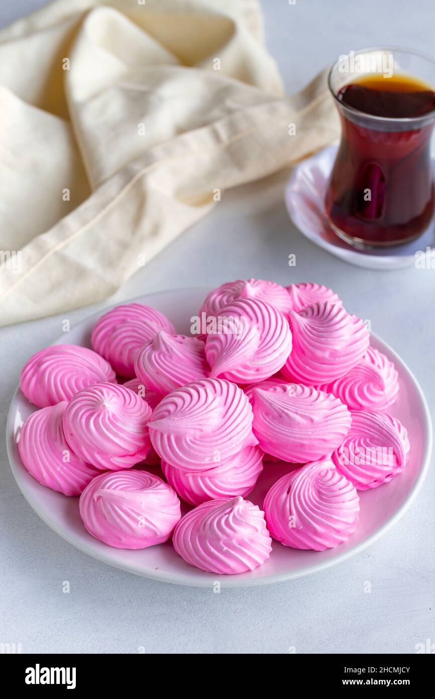 Piccoli meringui rosa in un piatto bianco. Scatto macro. Vista verticale Foto Stock
