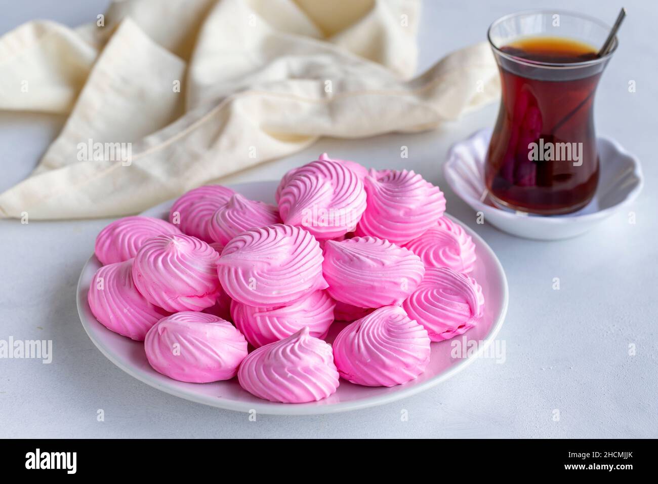 Piccoli meringui rosa in un piatto bianco. Scatto macro. Vista orizzontale Foto Stock