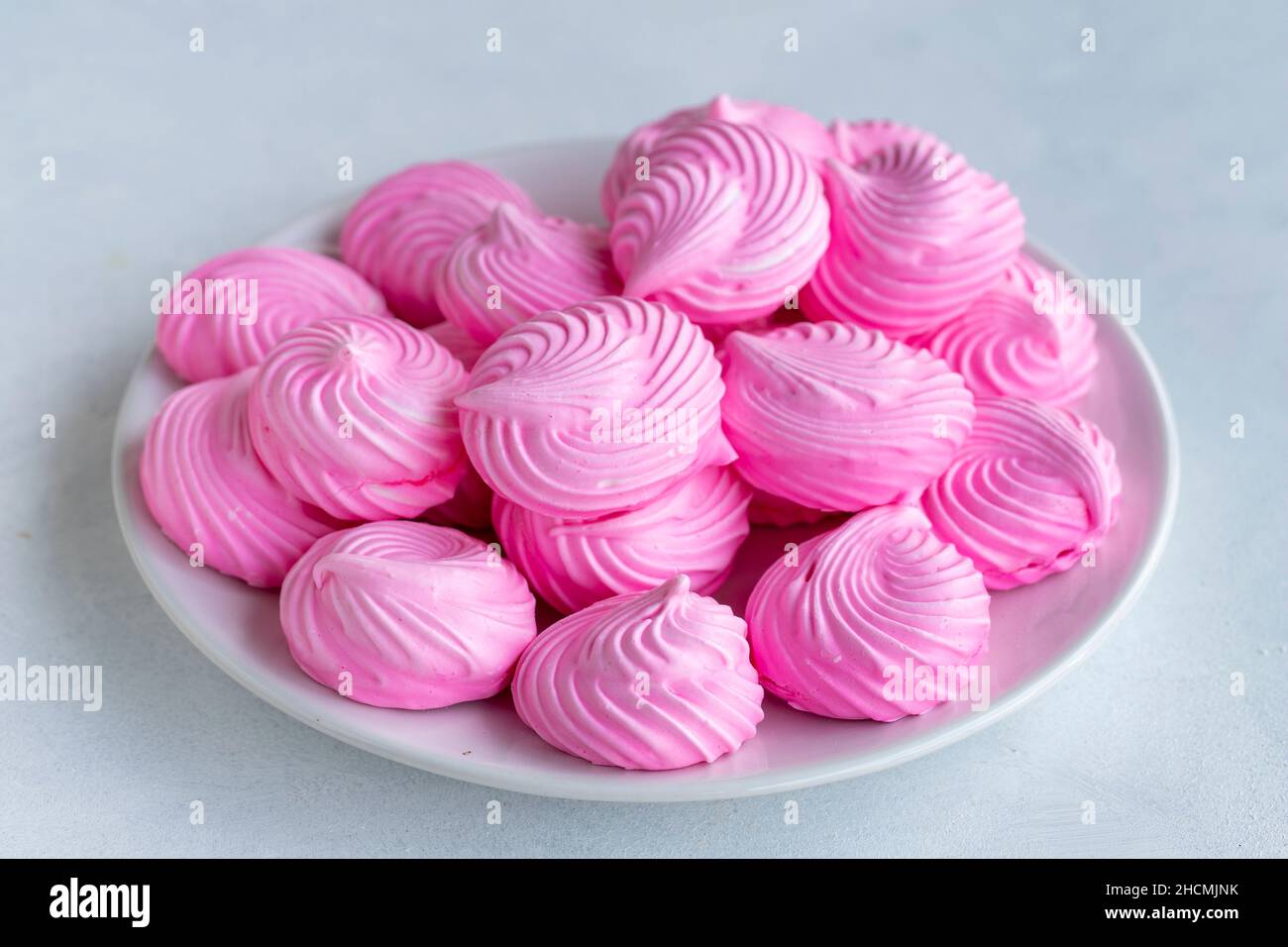 Piccoli meringui rosa in un piatto bianco. Scatto macro. Vista orizzontale Foto Stock