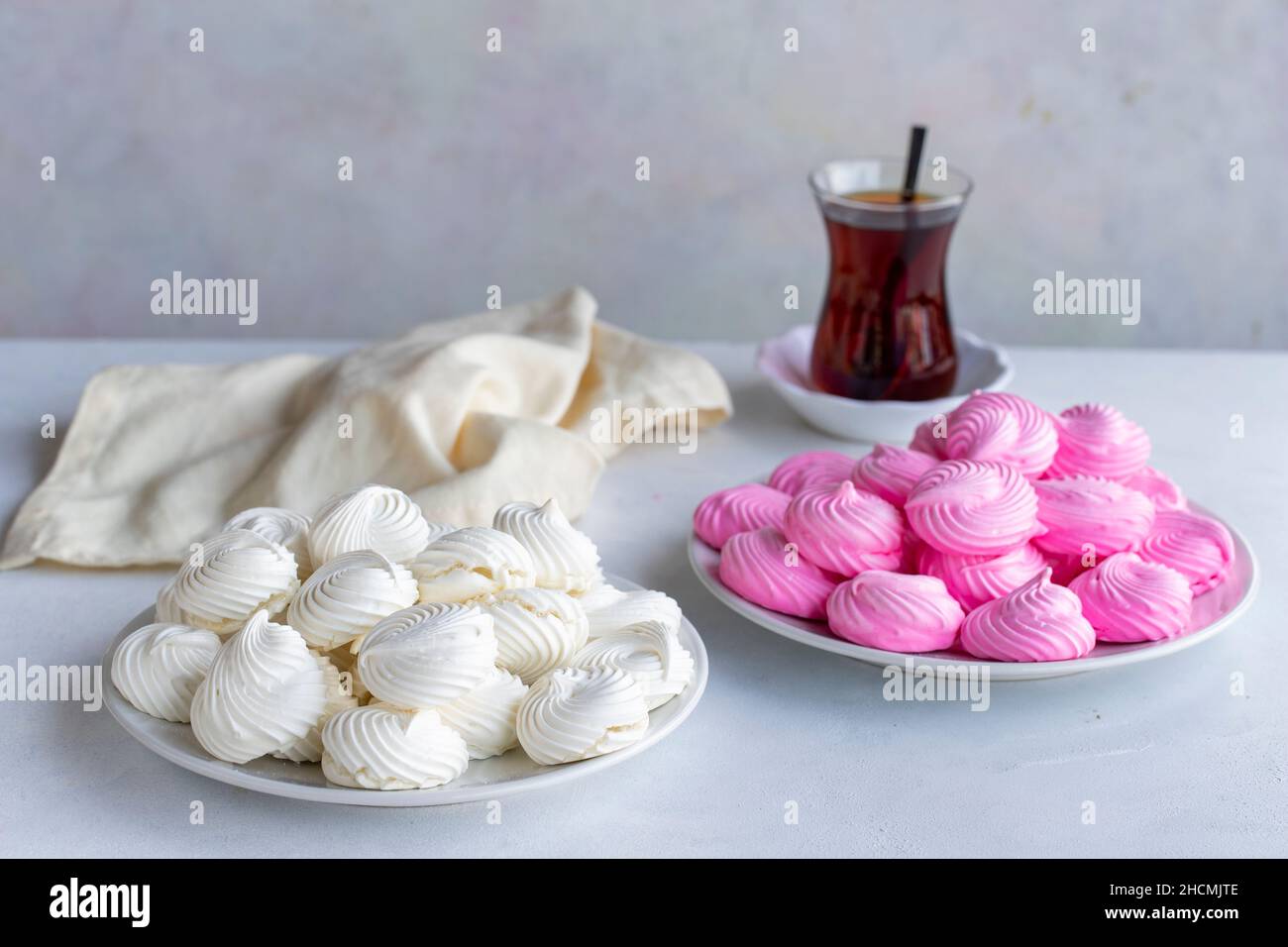 Piccole meringhe bianche e rosa in un piatto bianco. Scatto macro. Vista orizzontale Foto Stock